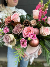 Load image into Gallery viewer, A bouquet of assorted flowers including pink and white roses, green pine cones, and red berries, wrapped in a decorative paper with a Christmas theme.