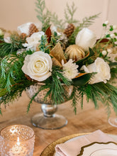 Load image into Gallery viewer, a festive holiday centerpiece with white flowers, fresh winter greens, gold ornaments and ribbon, and pinecones.