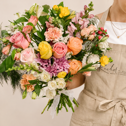 Person holding a colorful bouquet of flowers against a neutral background