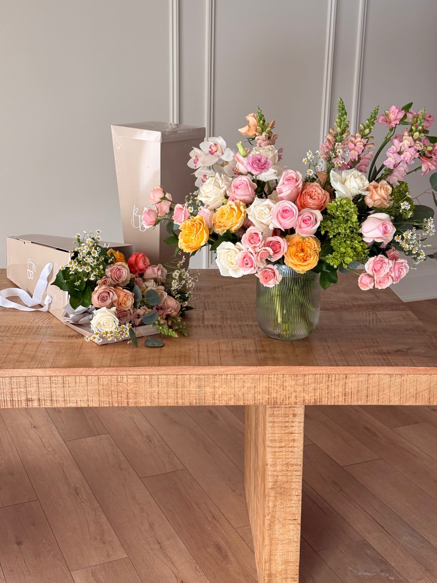 Floral arrangements on a wooden table with a neutral background