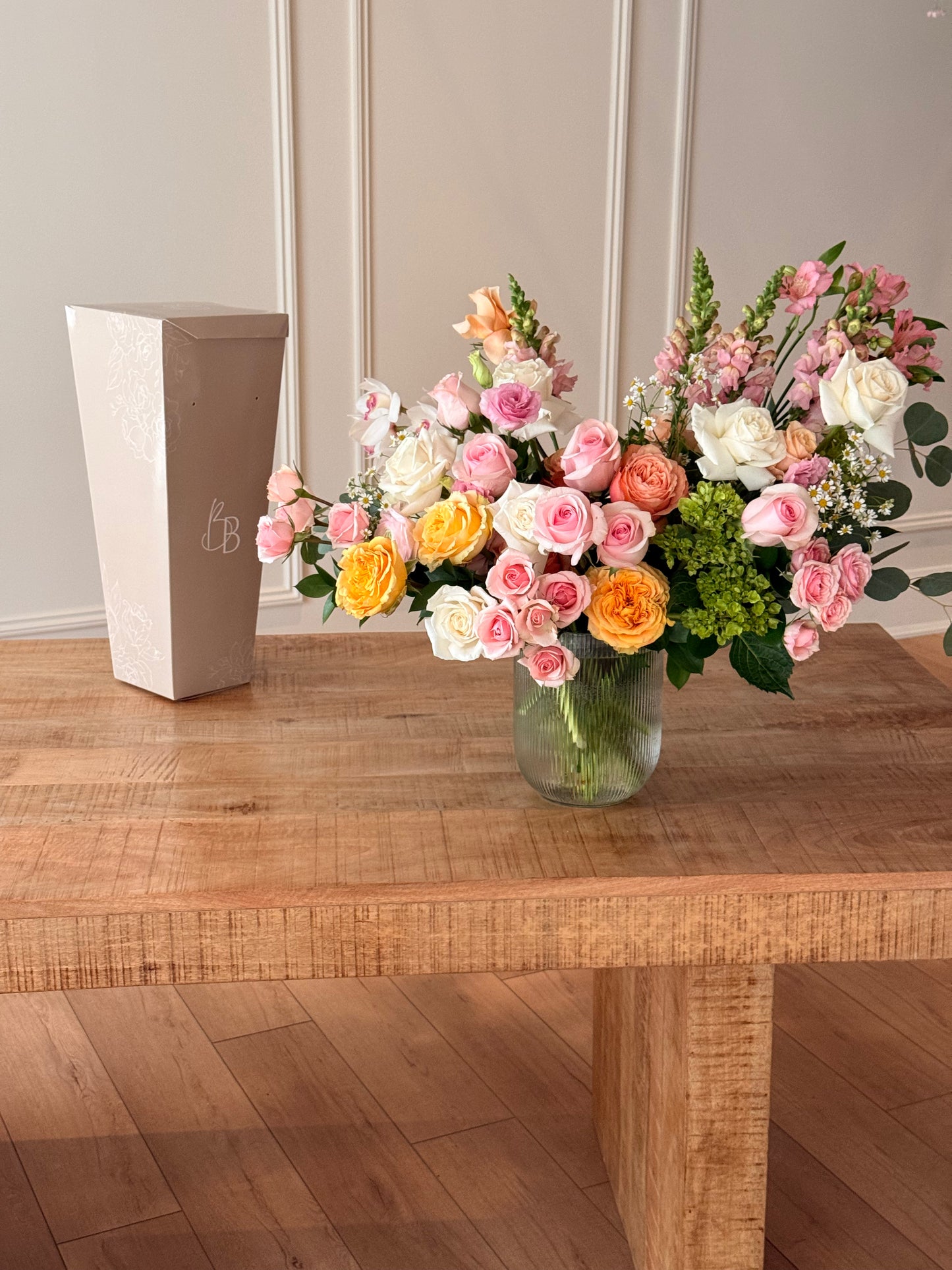 Bouquet of flowers in a clear vase on a wooden table with a neutral background