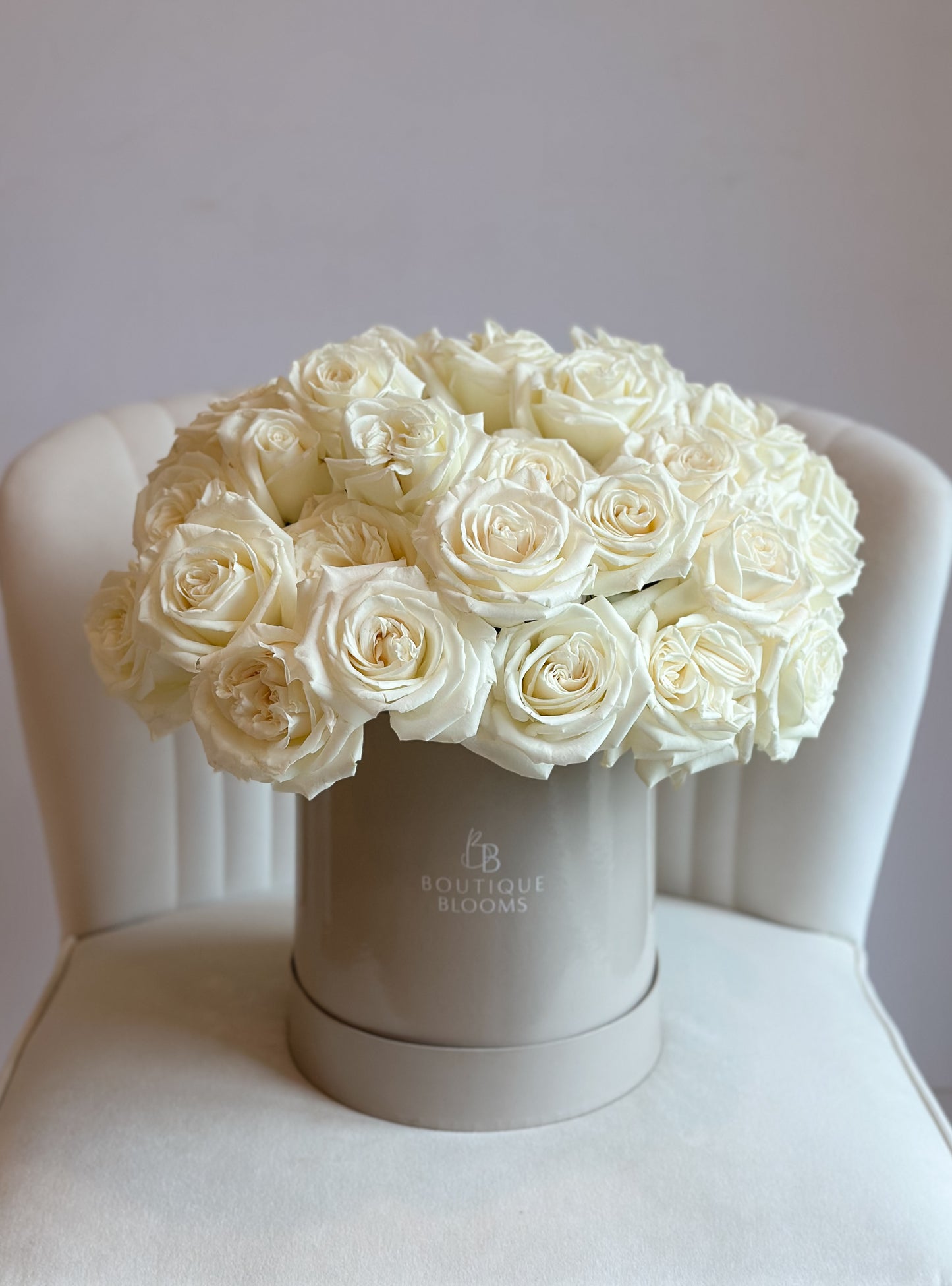Bouquet of white roses in a gray box on a white chair