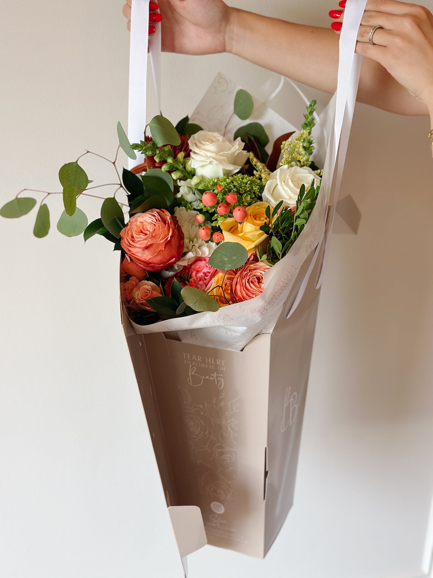 peach, yellow, and white florals in a bouquet delivered in a bag.