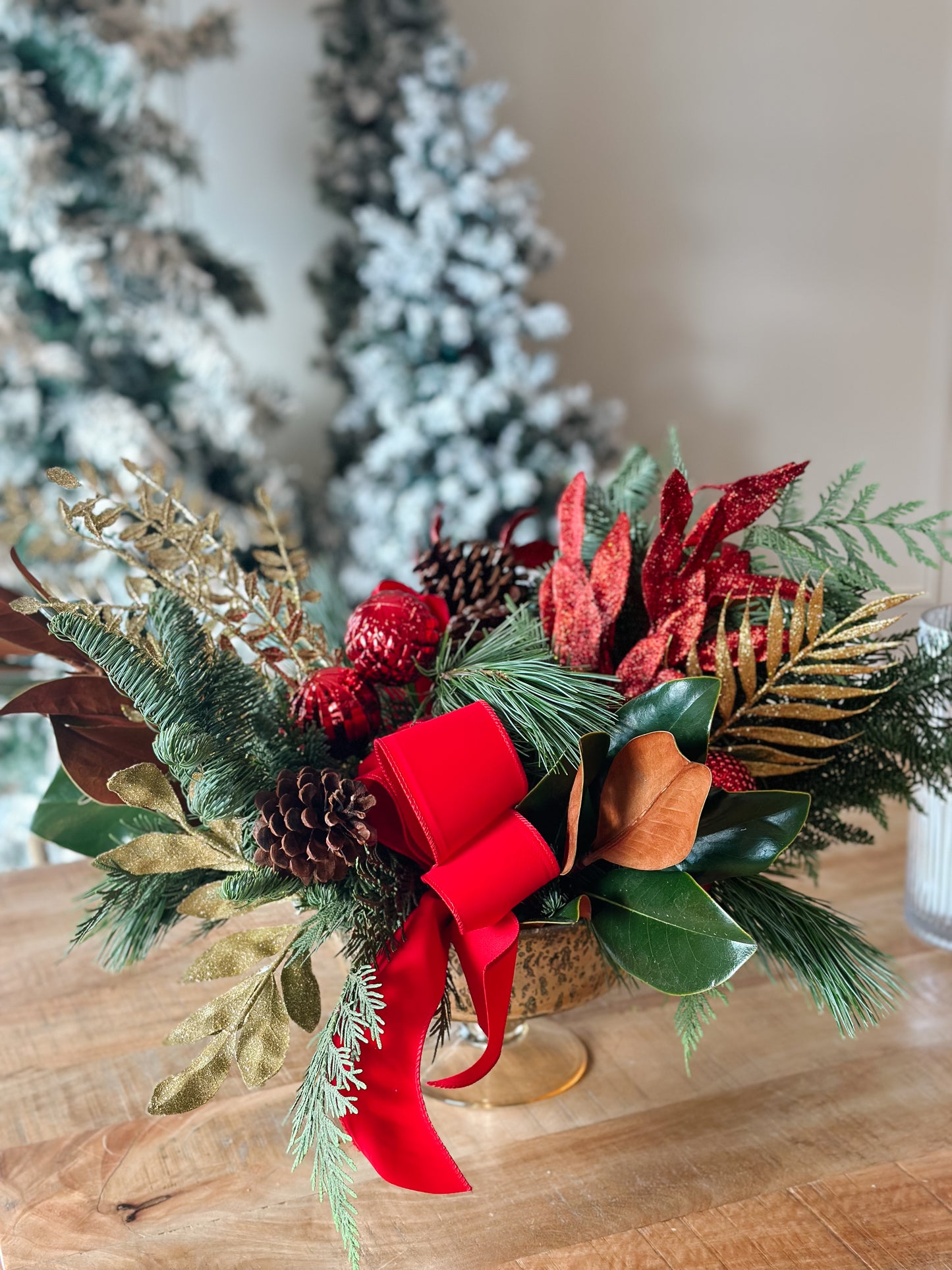 Decorative Christmas flower arrangement with red ribbons on a wooden surface.