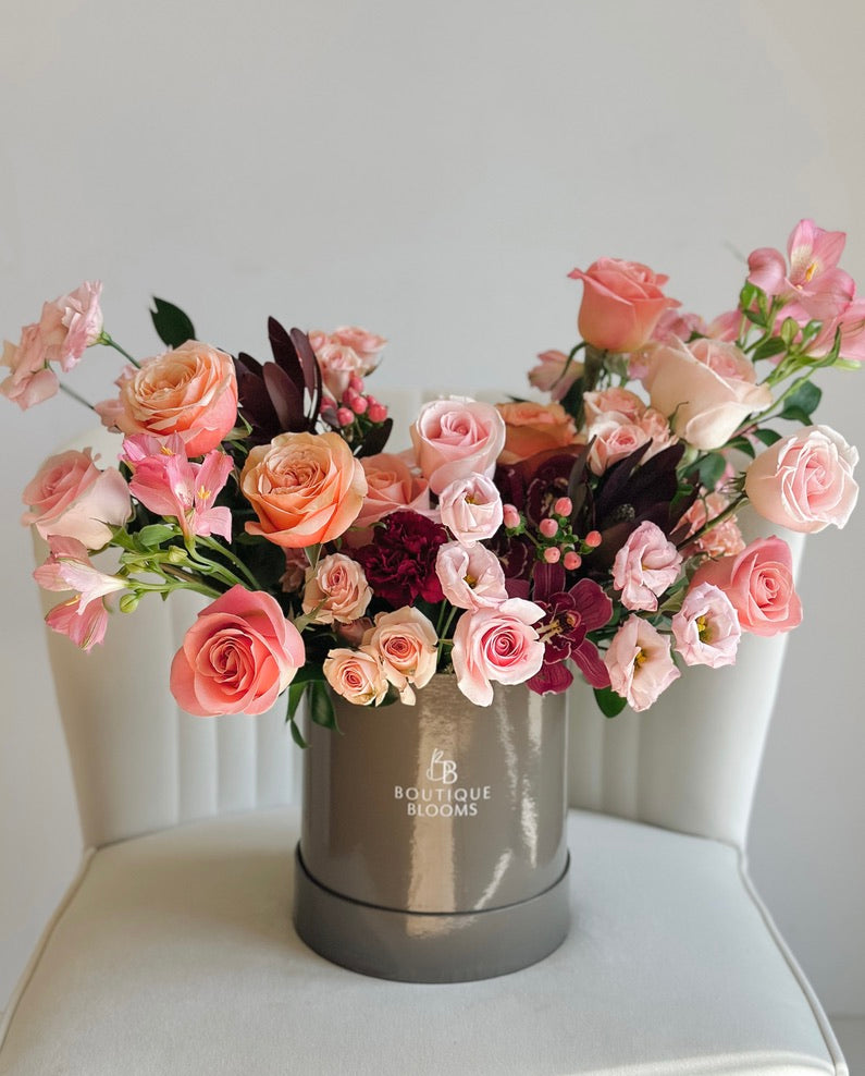 Bouquet of pink and purple flowers in a white box on a white background