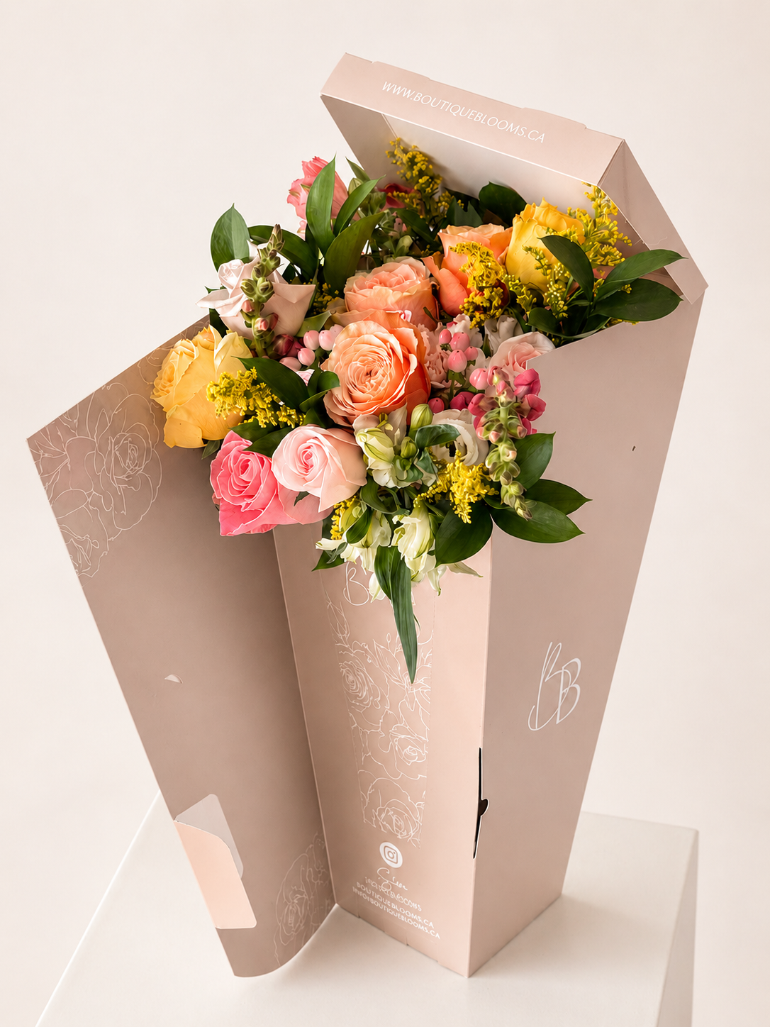 Colorful bouquet of flowers in a decorative box on a light background