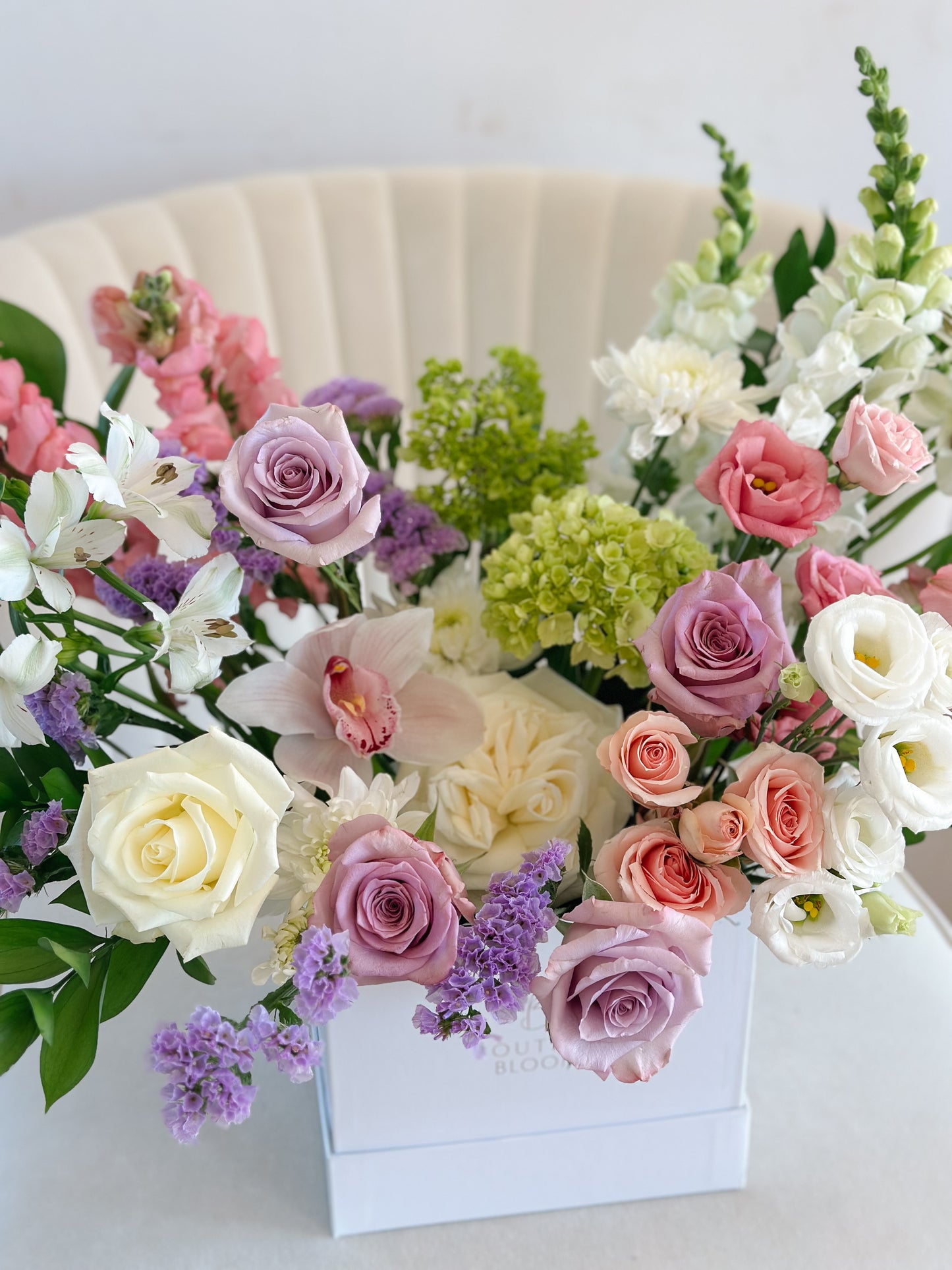 Bouquet of colorful flowers in a white box on a light background