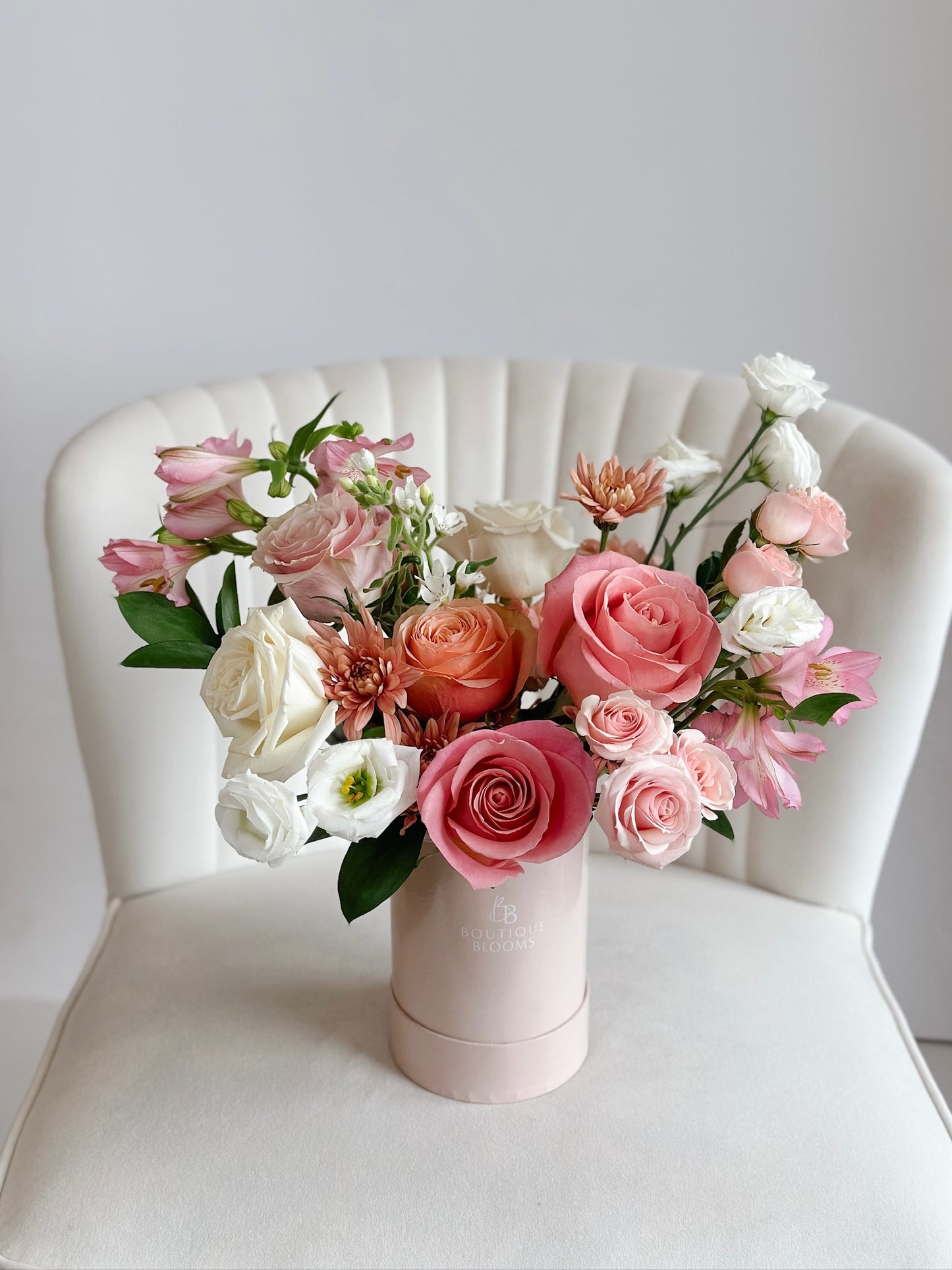 Blush pink and ivory roses with soft lisianthus and seasonal blooms arranged in a luxury Boutique Blooms hat box.