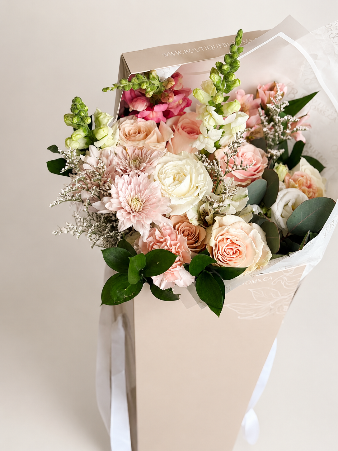 Blush and ivory roses arranged in a luxury flower bag with fresh greenery for Toronto flower delivery.