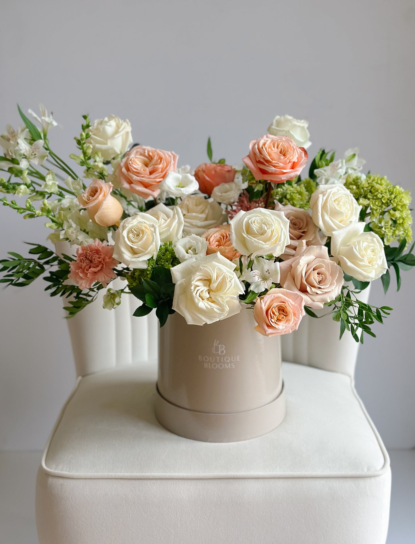 Champagne garden roses, ivory roses, soft blush blooms, and green hydrangea arranged in a premium Boutique Blooms hat box.