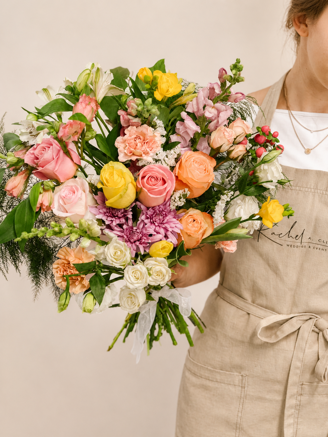 Person holding a colorful bouquet of flowers against a neutral background