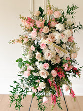 Load image into Gallery viewer, A standing sympathy spray arranged with a variety of fresh flowers including roses and other floral blooms in shades of pink, white, and green.

