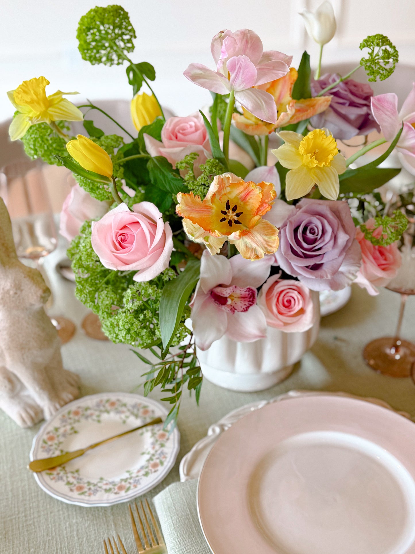 Colorful flower arrangement on a table with plates and cutlery