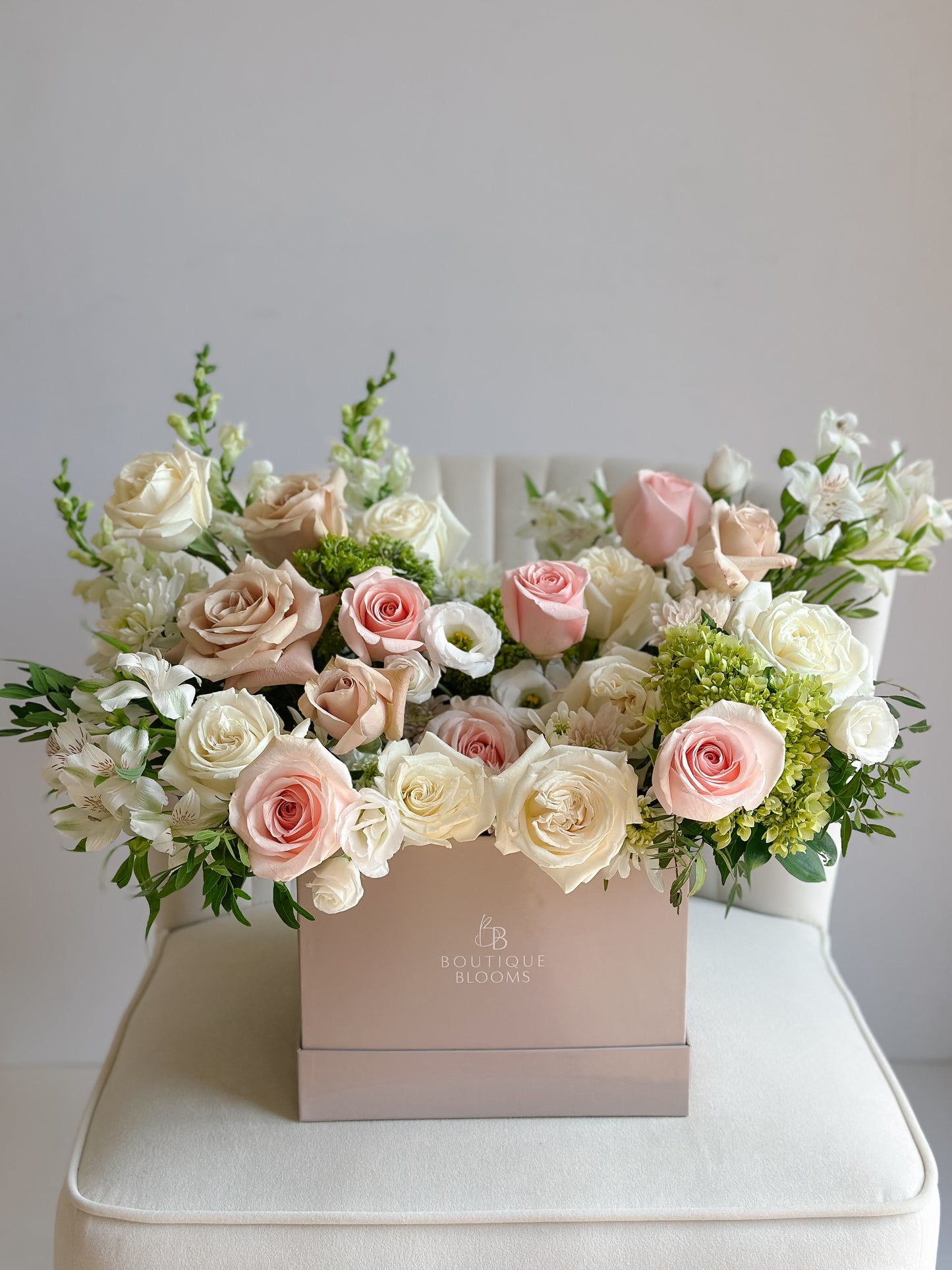 Blush pink roses, ivory roses, green hydrangea, and delicate white florals arranged in a luxury Boutique Blooms flower box.