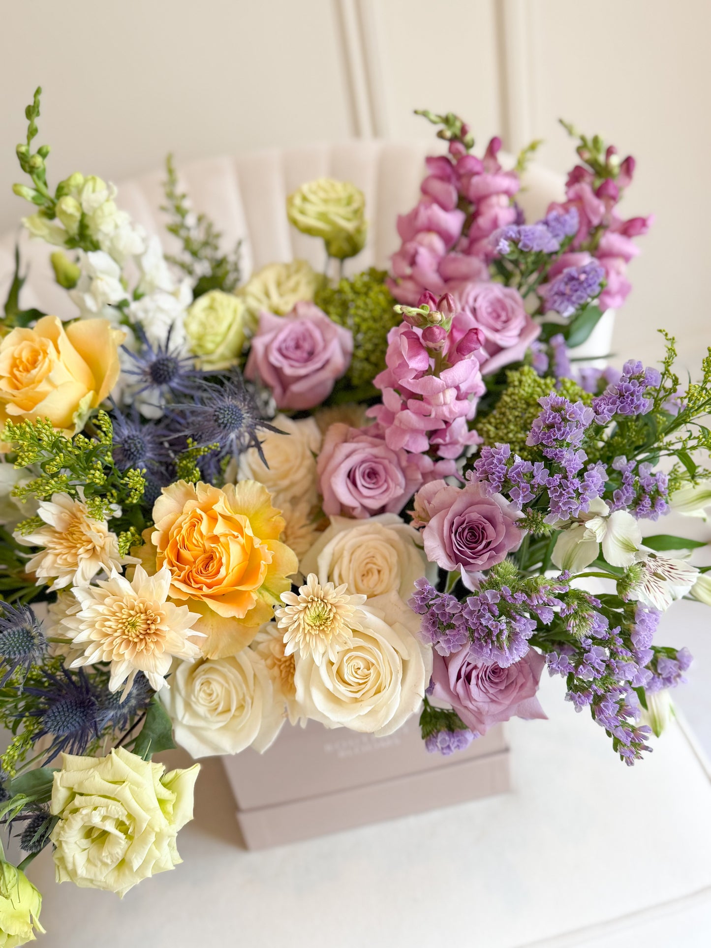 Colorful flower arrangement with roses and hydrangeas in a box on a white surface.