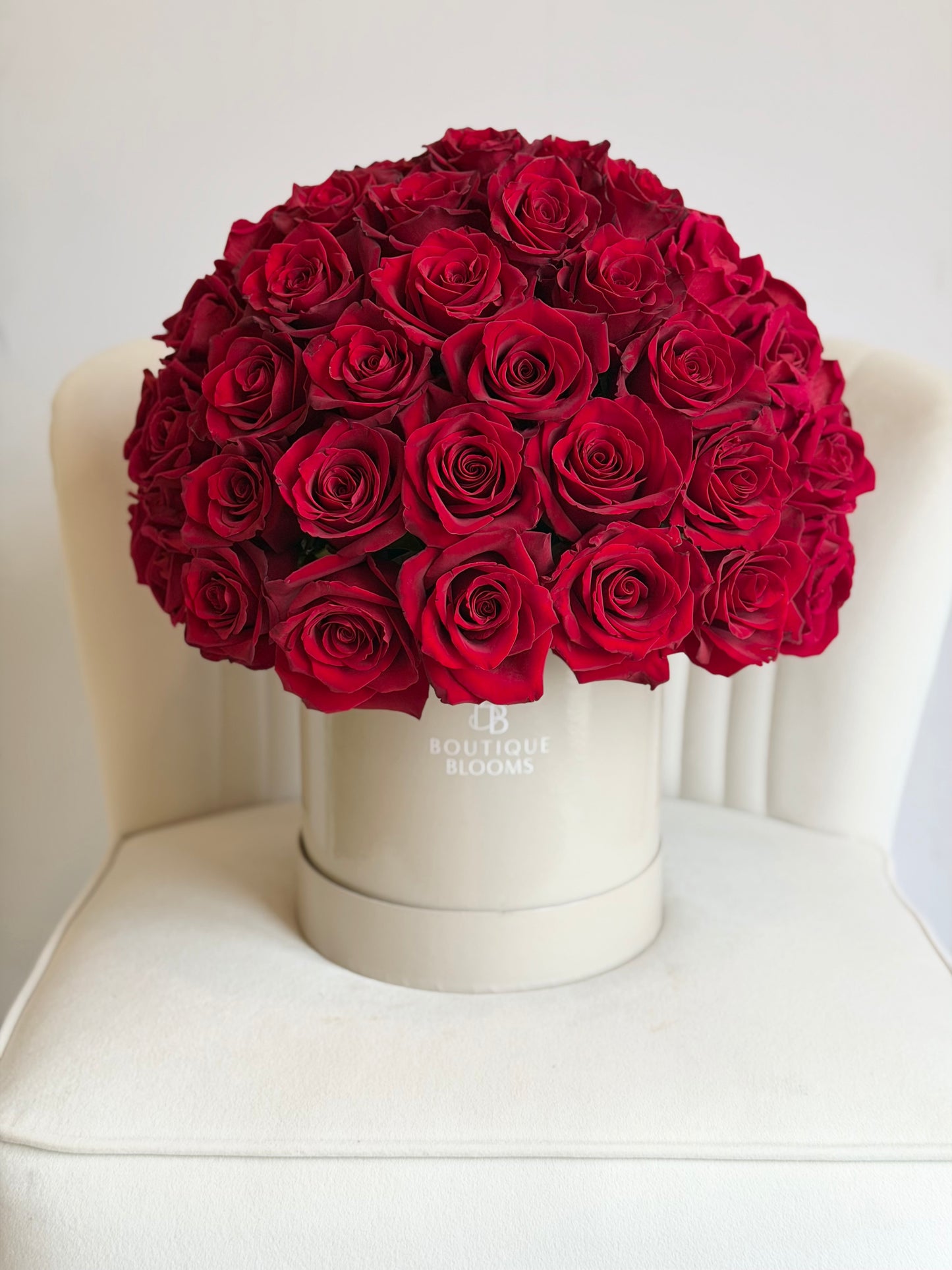 red rose arrangement in a hat box on a chair. 