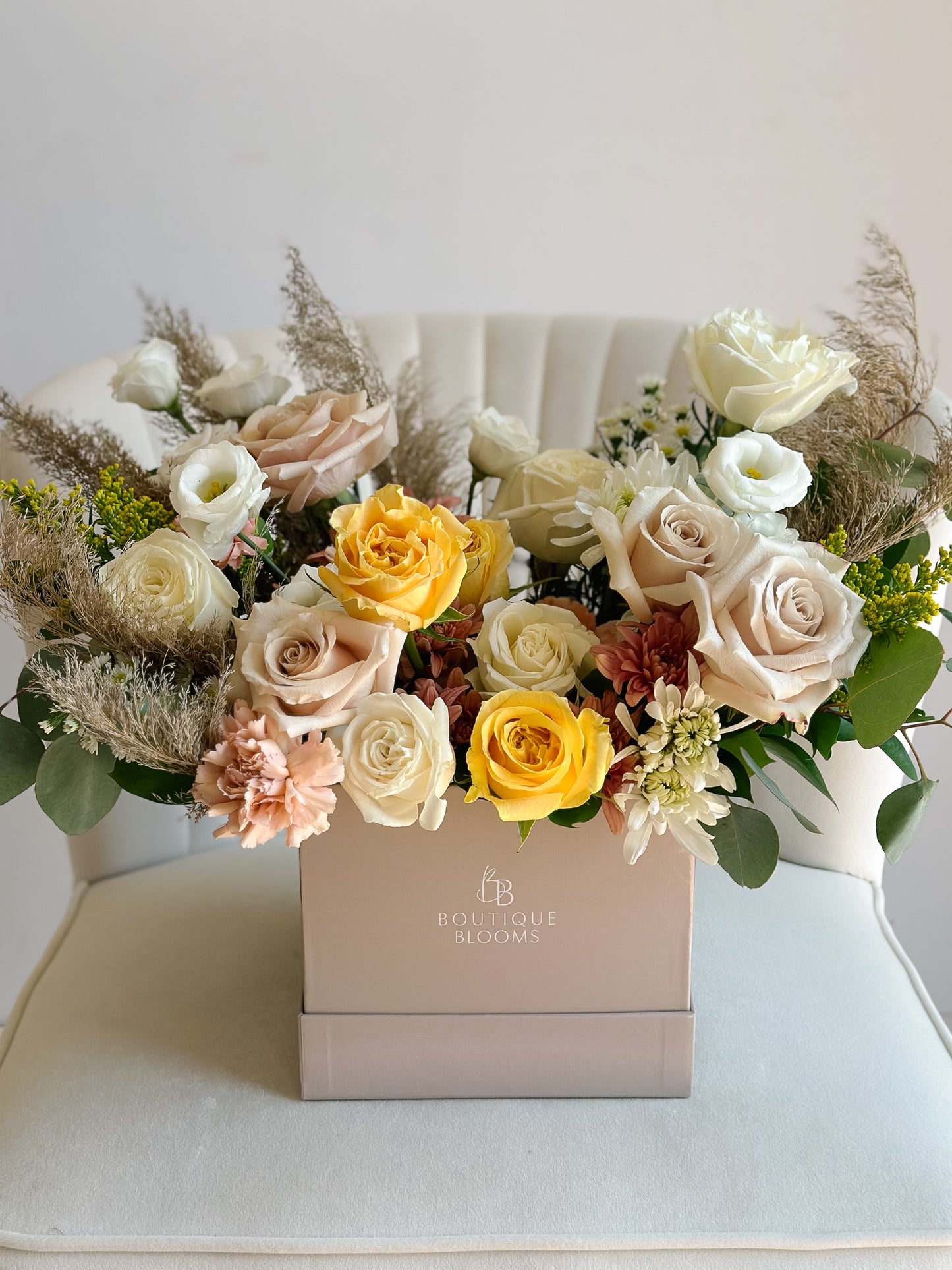 Golden yellow roses, champagne roses, ivory blooms, pampas accents, and seasonal florals arranged in a luxury Boutique Blooms box.