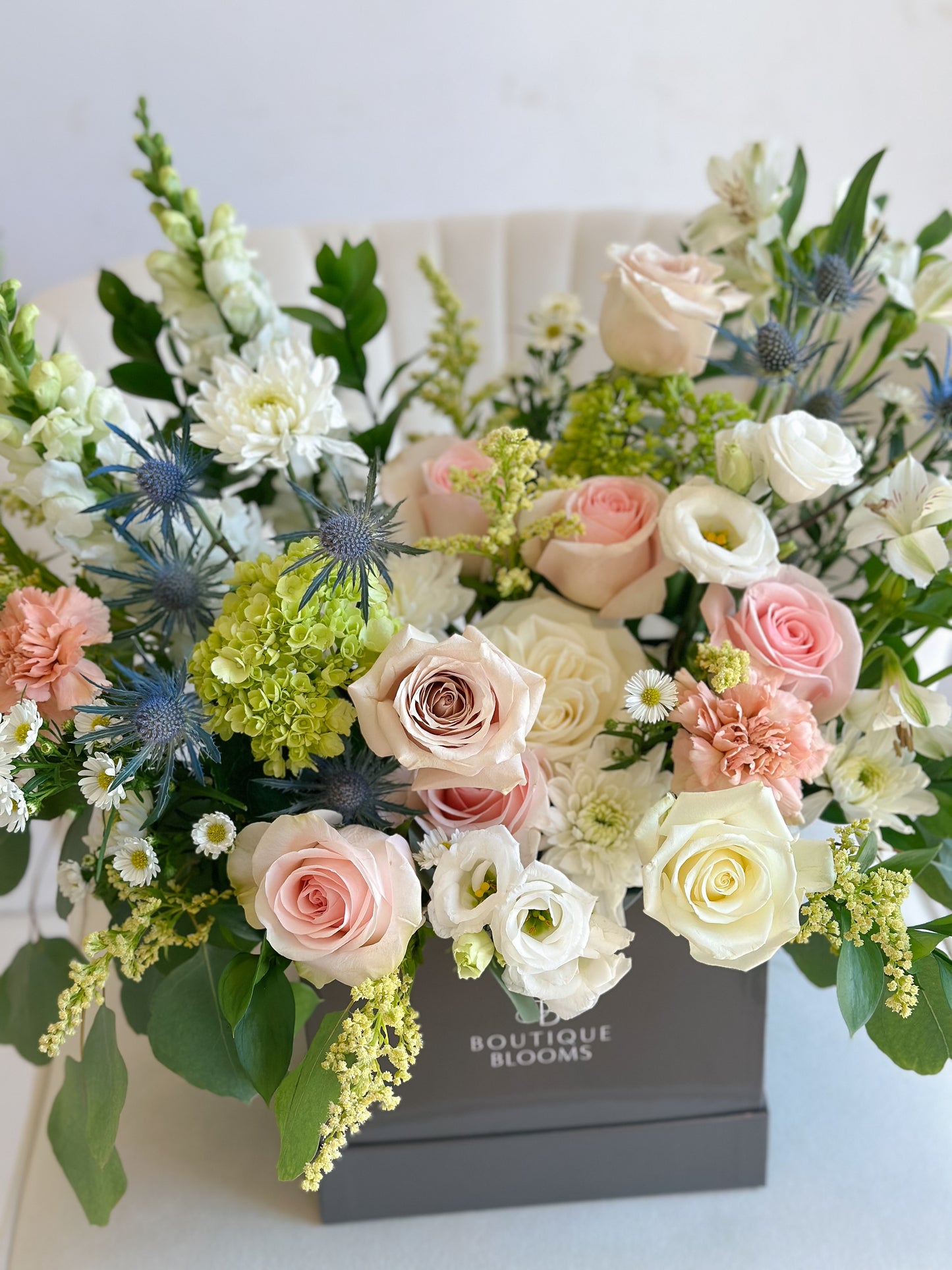 Bouquet of flowers in a box with 'Boutique Blooms' branding on a light background