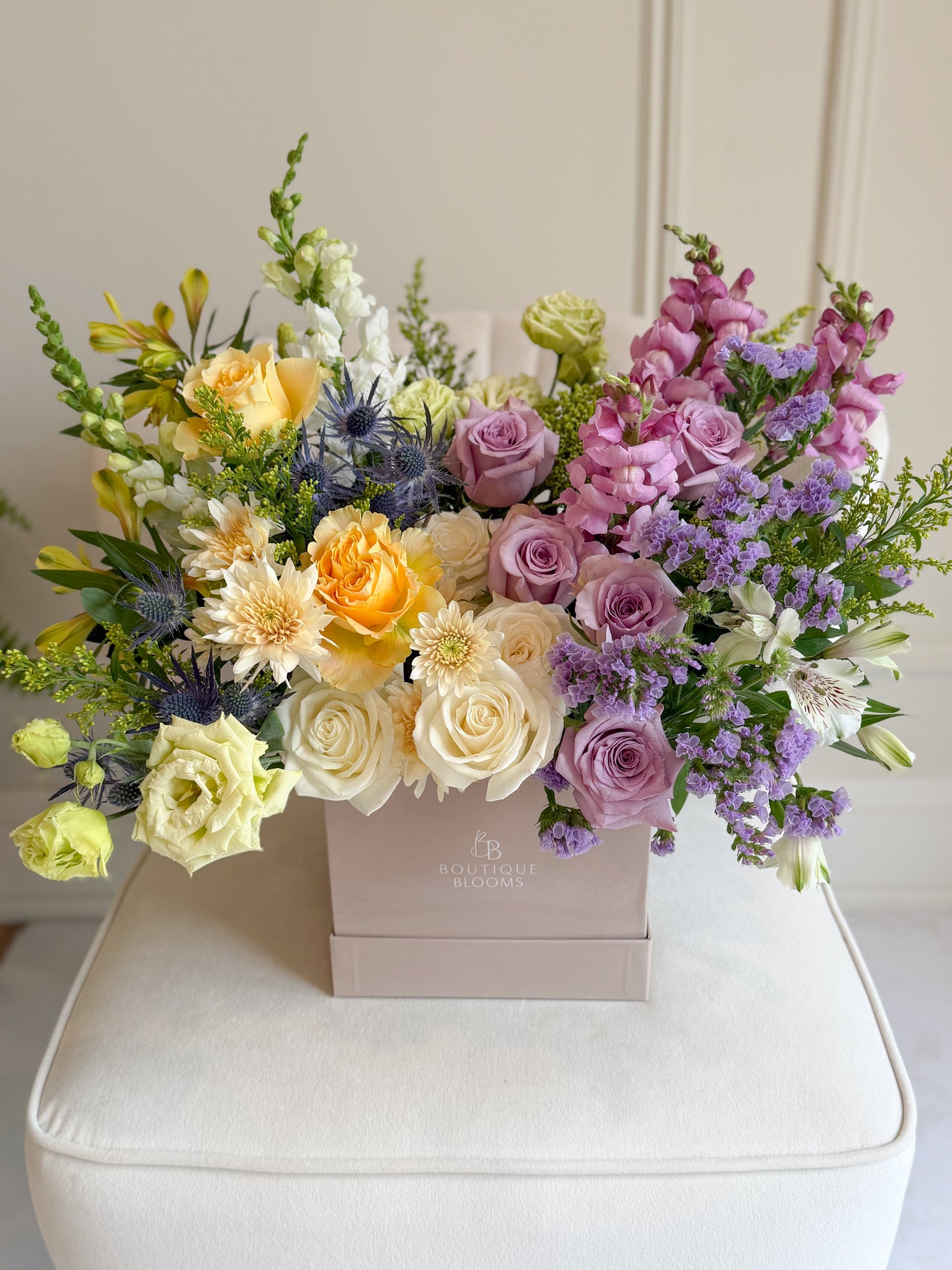 Colorful flower arrangement in a box on a white surface with a neutral background