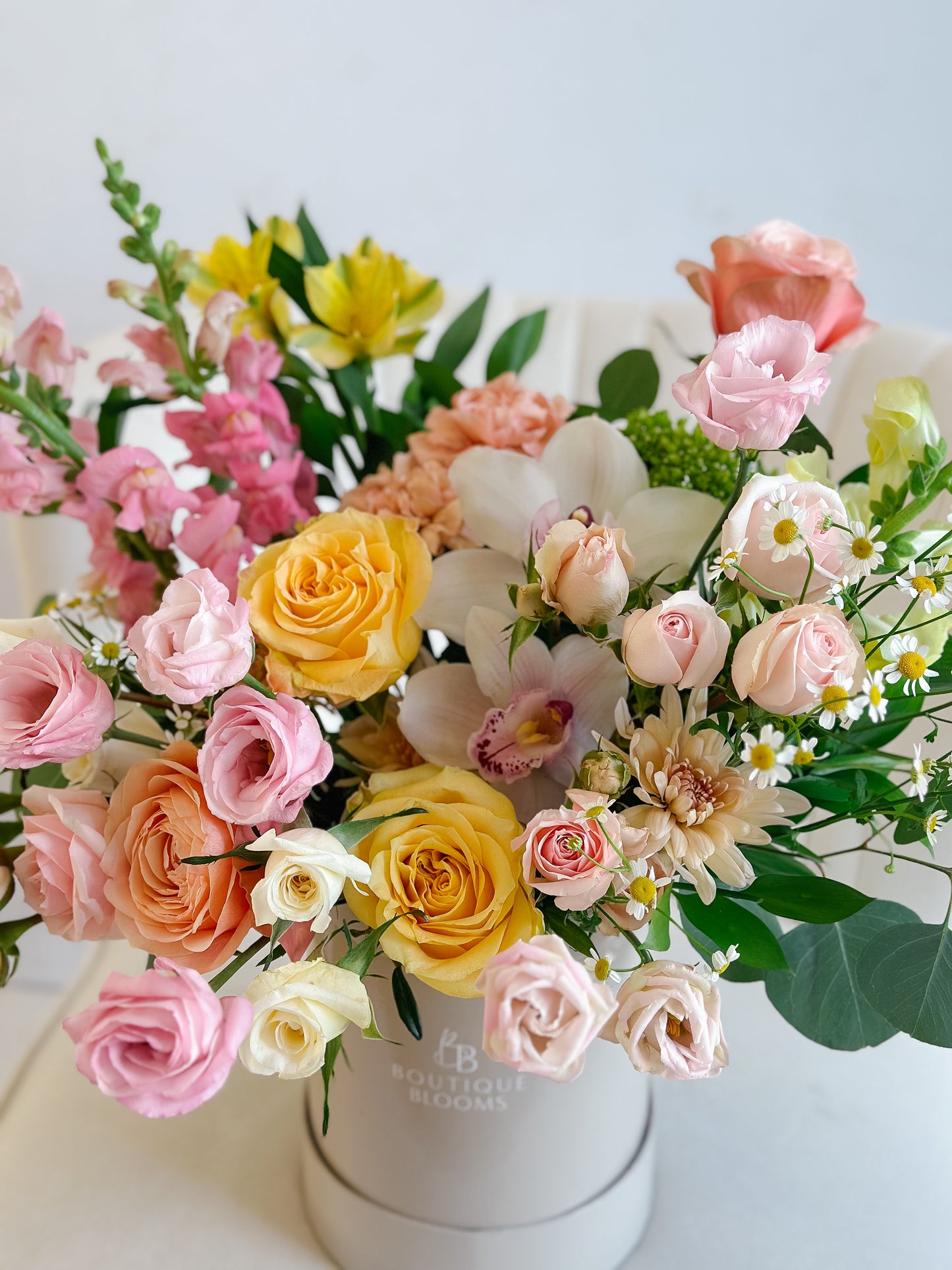 Bouquet of colorful flowers in a white box on a light background