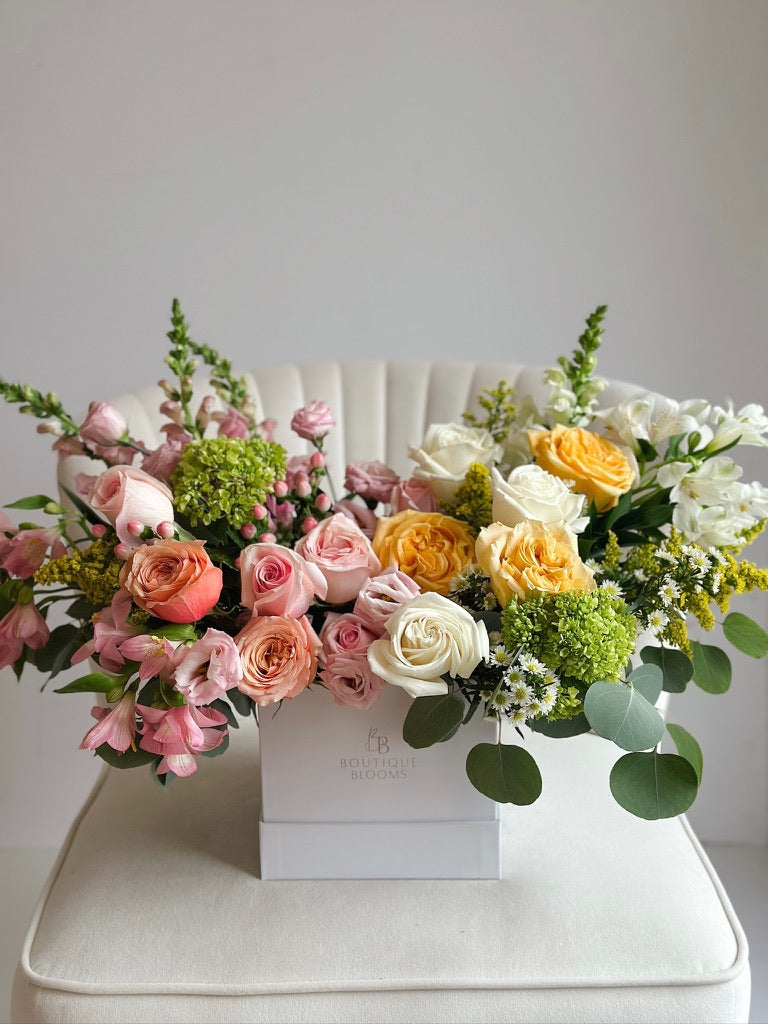 Blush, ivory, and golden garden roses accented with green hydrangea, eucalyptus, and seasonal florals in a luxury flower box.