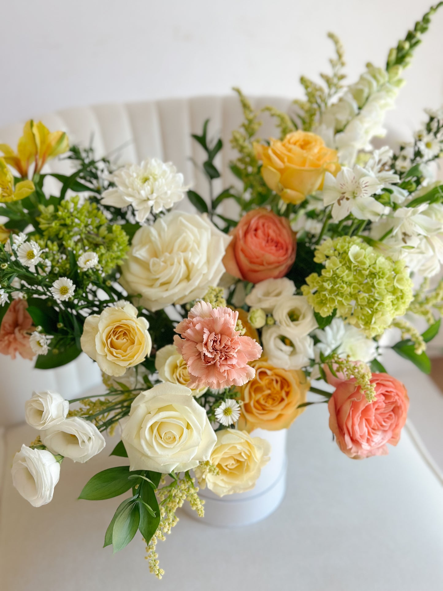Pastel roses, hydrangea, and seasonal blooms arranged in a modern white floral box with fresh greenery.