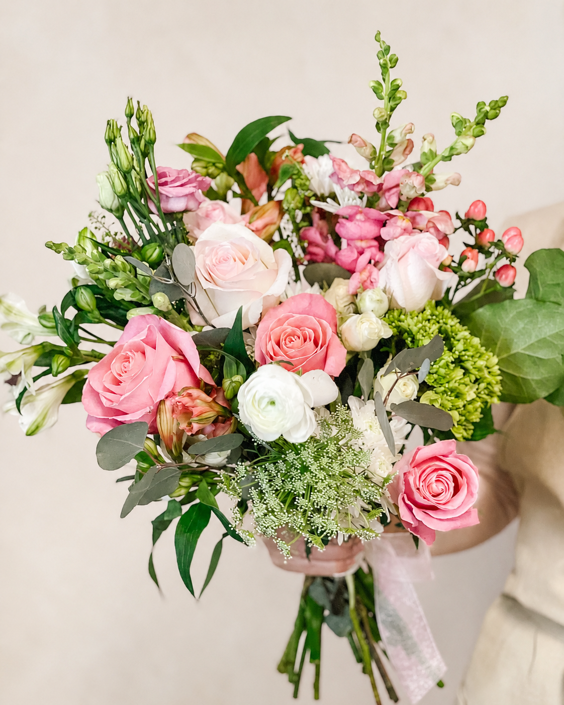 Bouquet of pink and white roses with greenery on a light background