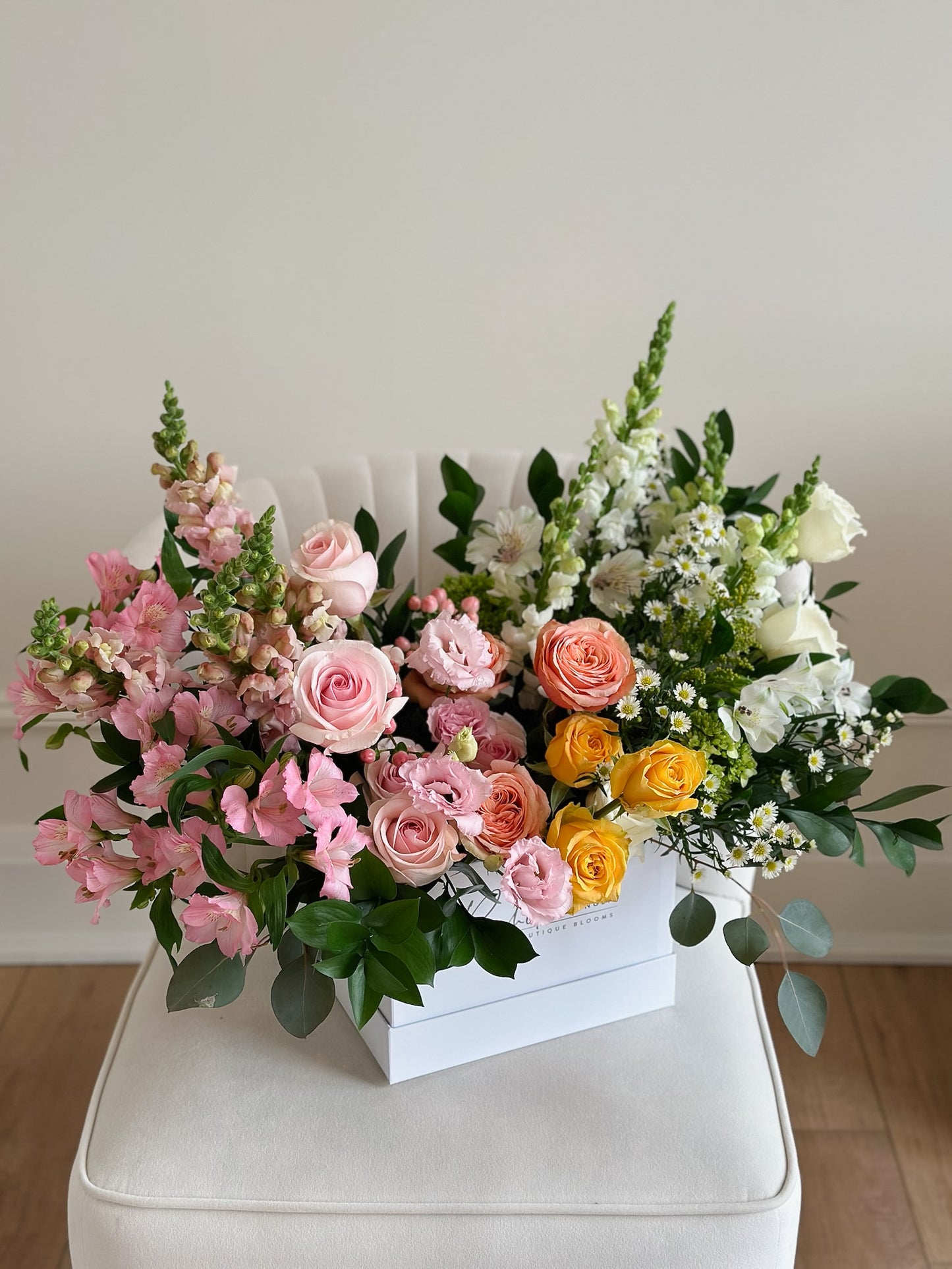 a stunning mixture of pink, yellow, and white florals featuring premium roses, snap dragons, and alstroemeria. 
