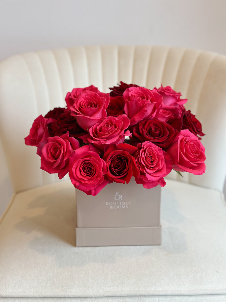 Bouquet of red and pink roses in a box on a white chair