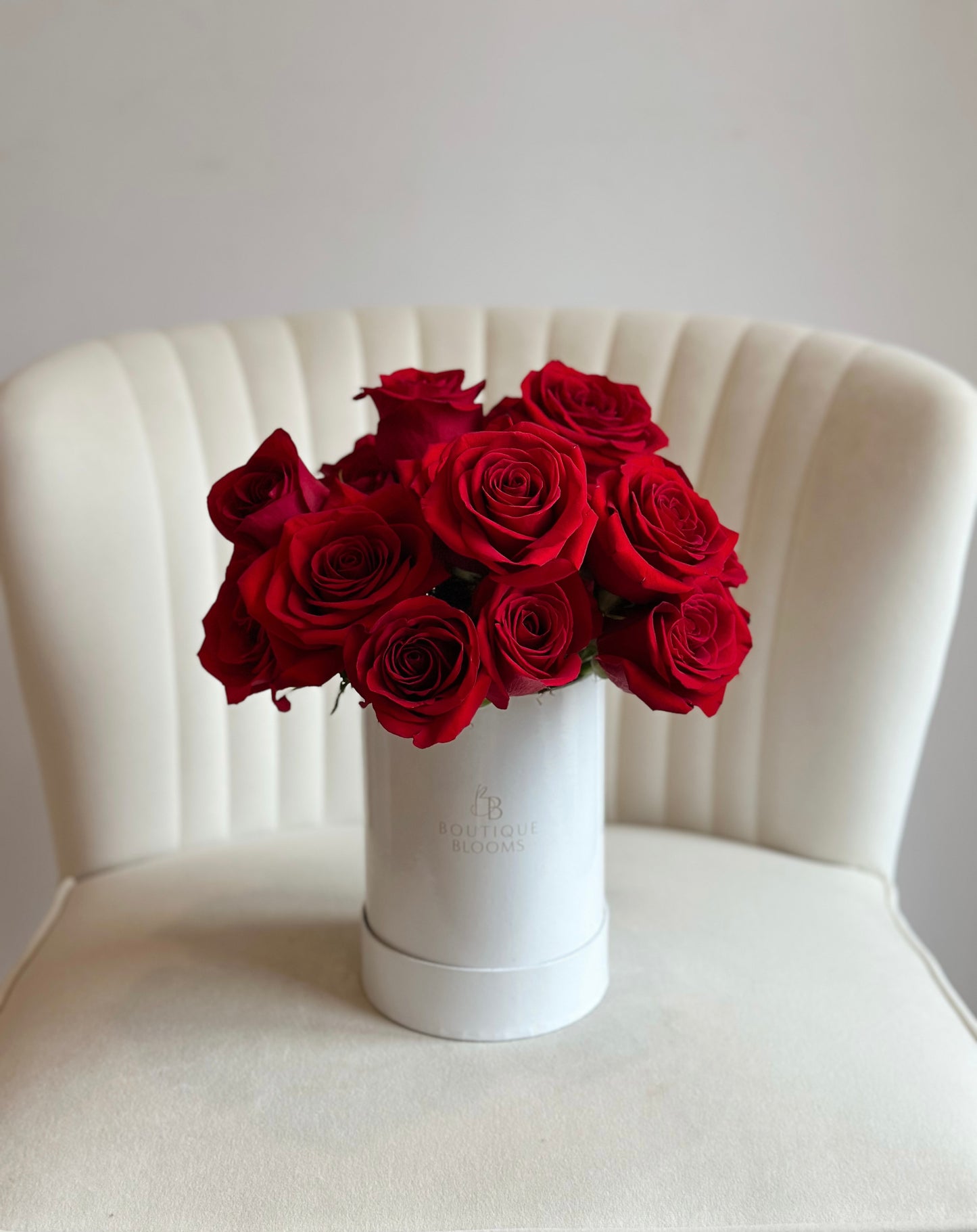 premium red rose arrangement in a white box on a chair