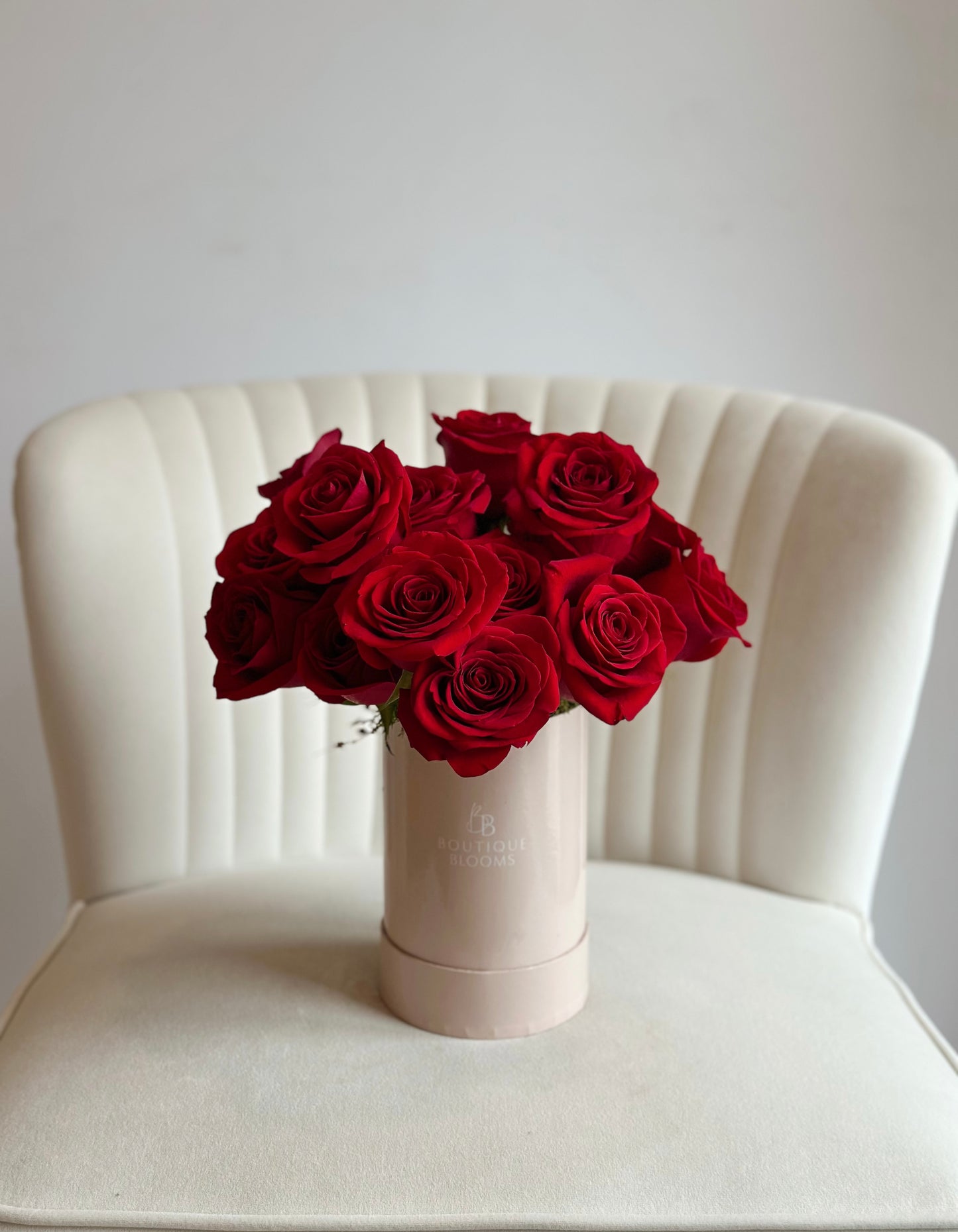 red rose bouquet in a taupe box on a white chair