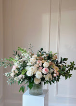 Load image into Gallery viewer, white sympathy arrangement designed in a clear ribbed vase with white roses and hints of pink and greenry.
