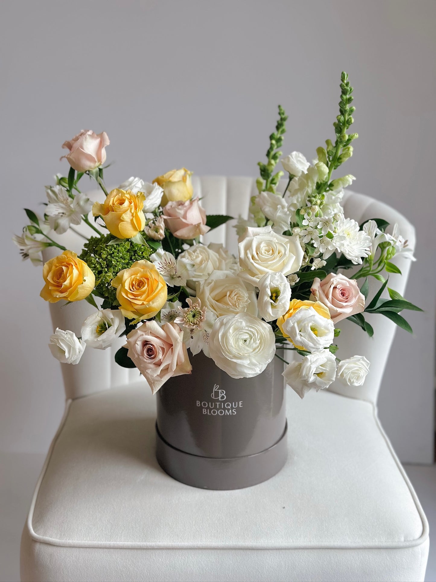 Floral arrangement in a gray box on a white surface with a light gray background