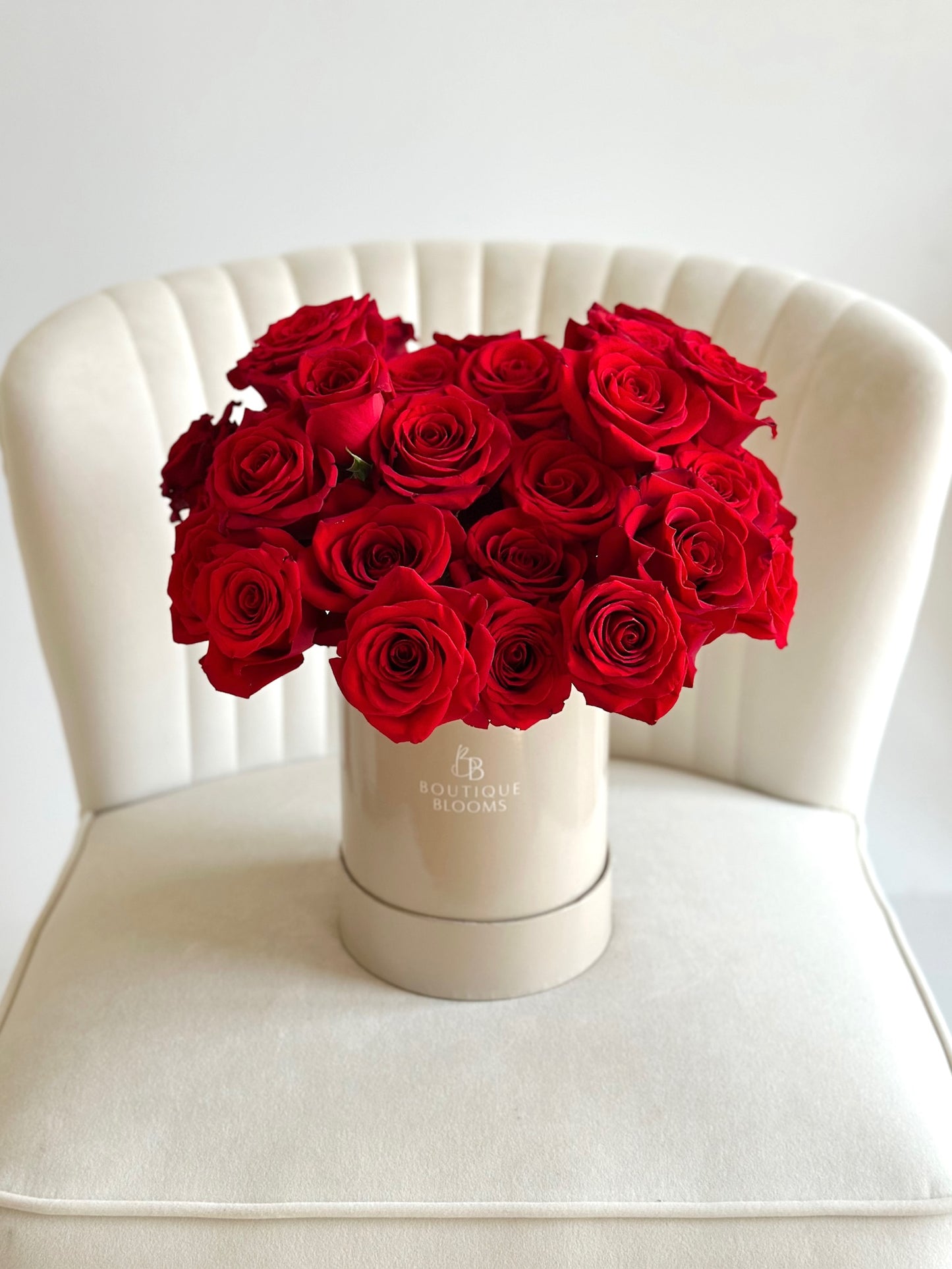 Premium bouquet of red roses designed in taupe box on white chair