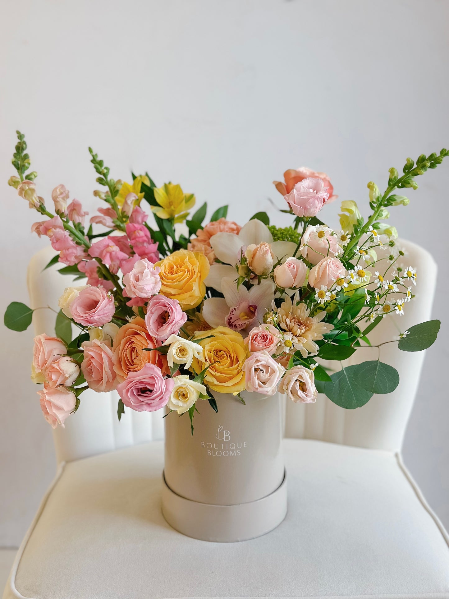 Floral arrangement in a white box on a white chair with a light gray background