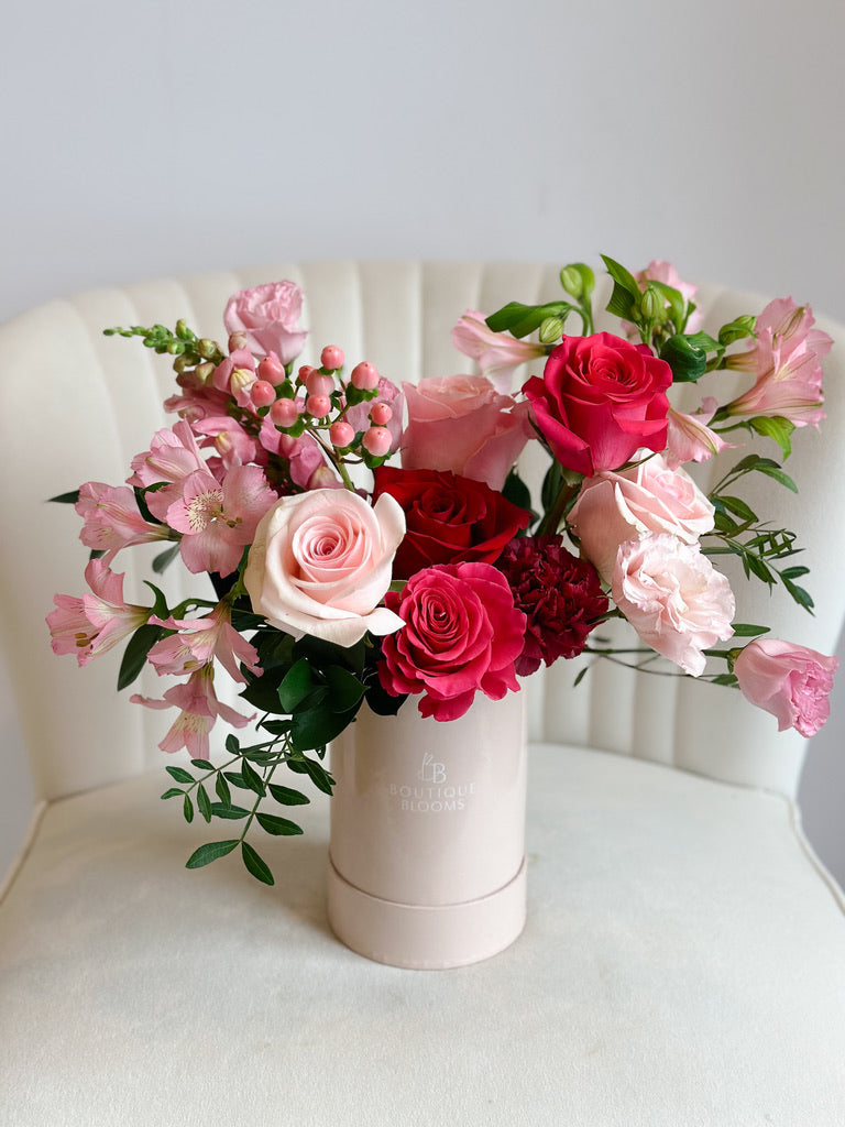 Bouquet of pink, red, and white flowers in a white vase on a light background