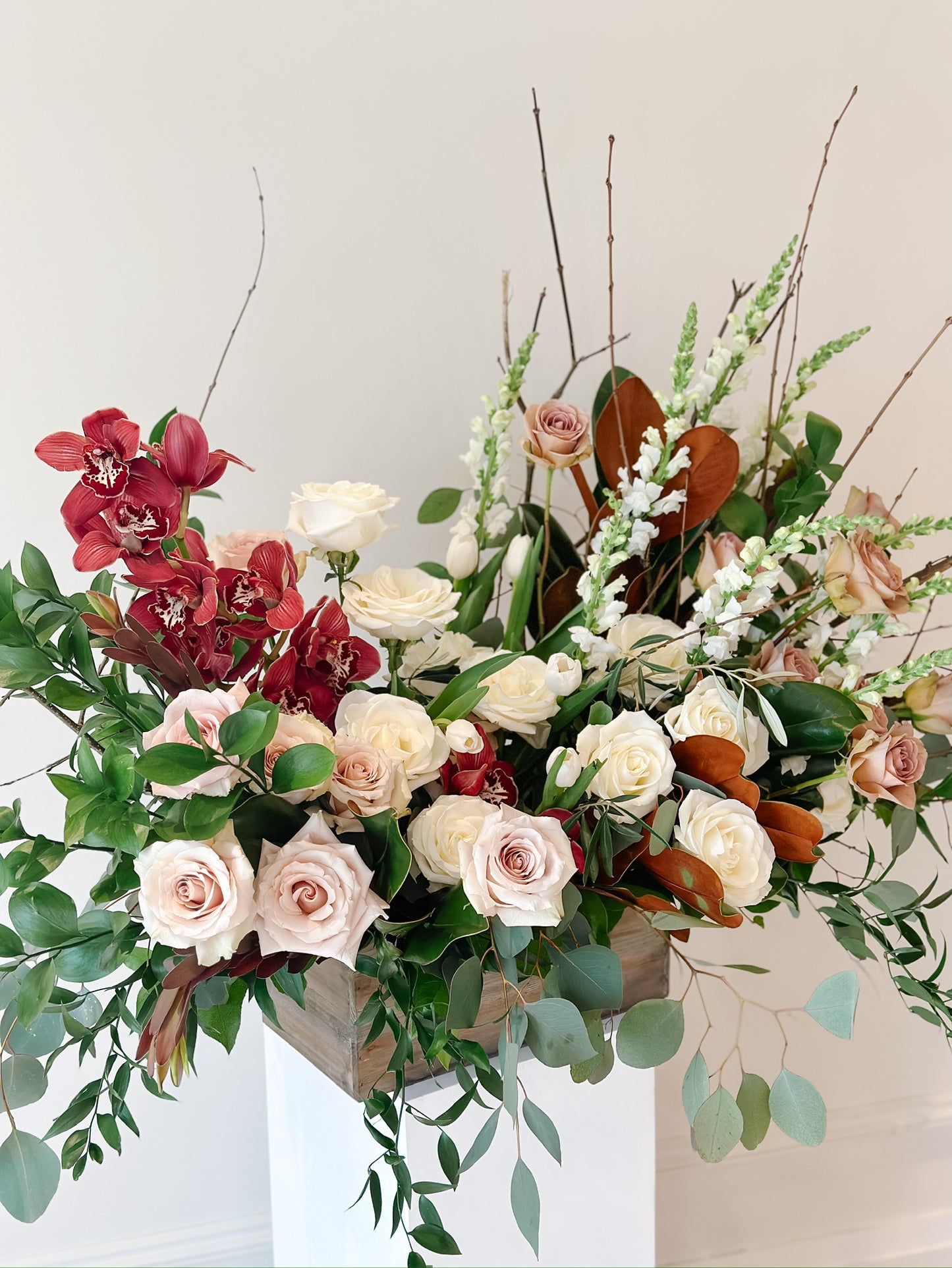 sympathy arrangement with orchids, roses, greenery, in a wood box