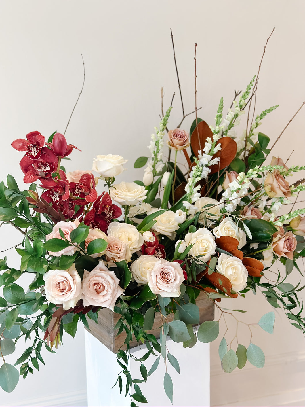 sympathy arrangement with orchids, roses, greenery, in a wood box