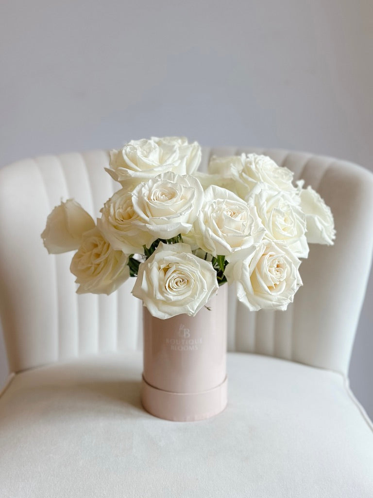 Bouquet of white roses in a pink vase on a white chair