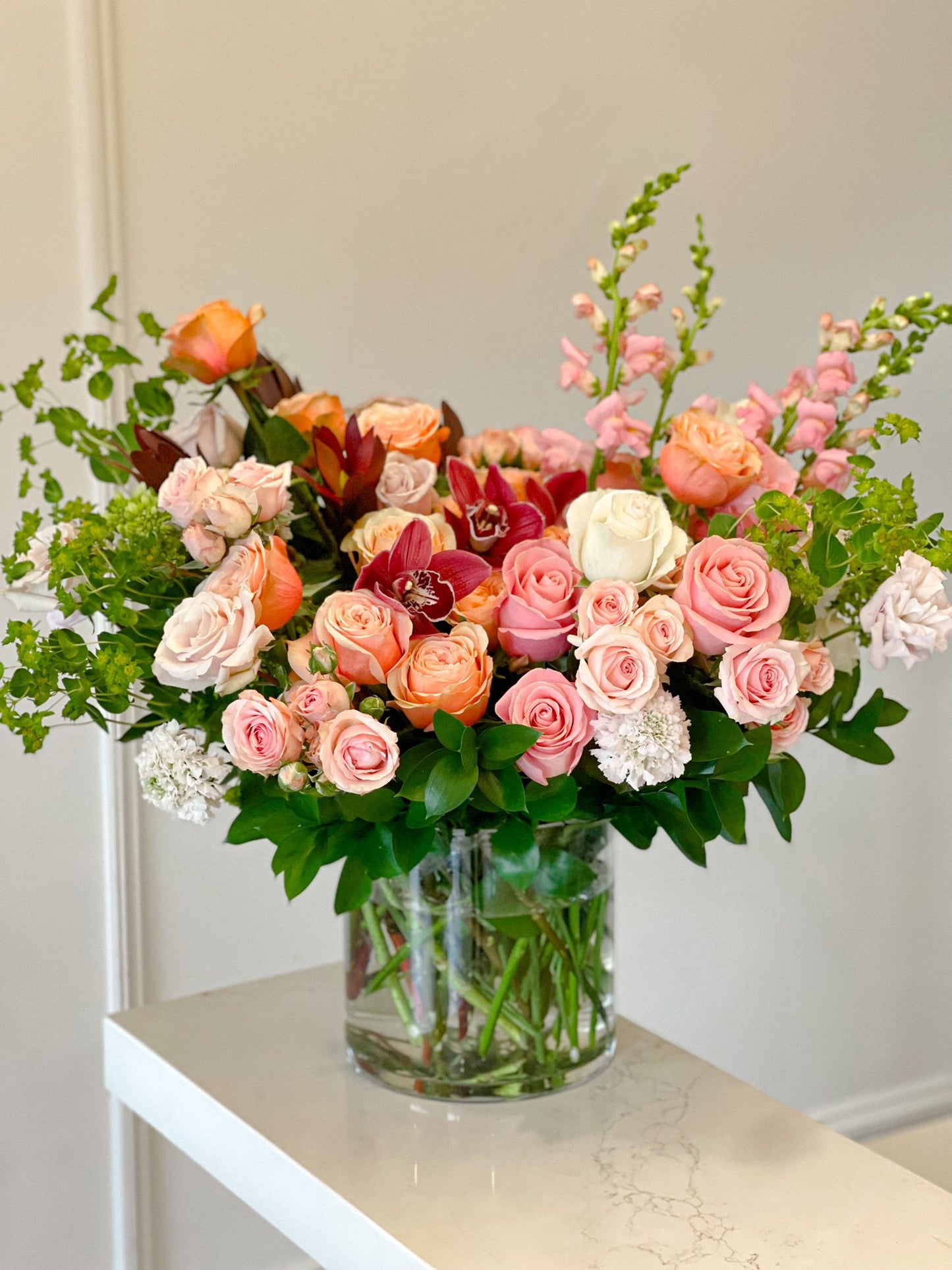 Bouquet of flowers in a clear vase on a white surface with a neutral background