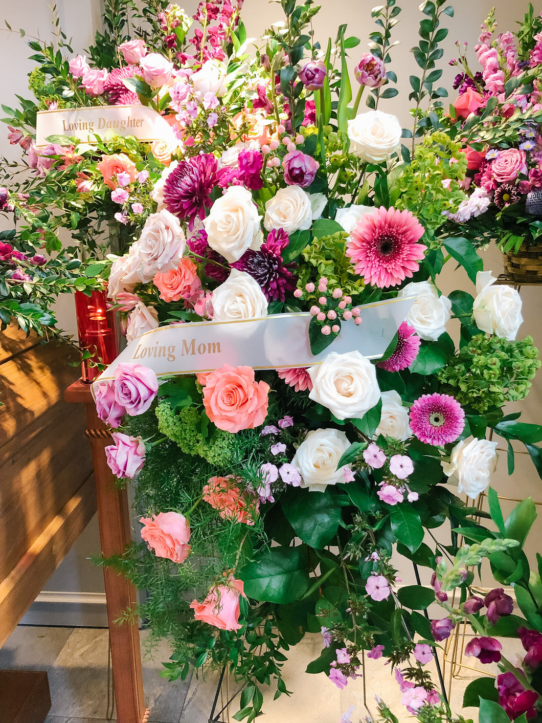 A standing sympathy spray arrangement of fresh flowers with a variety of colors, predominantly pink and green, with a card that reads 'Thinking of You'.