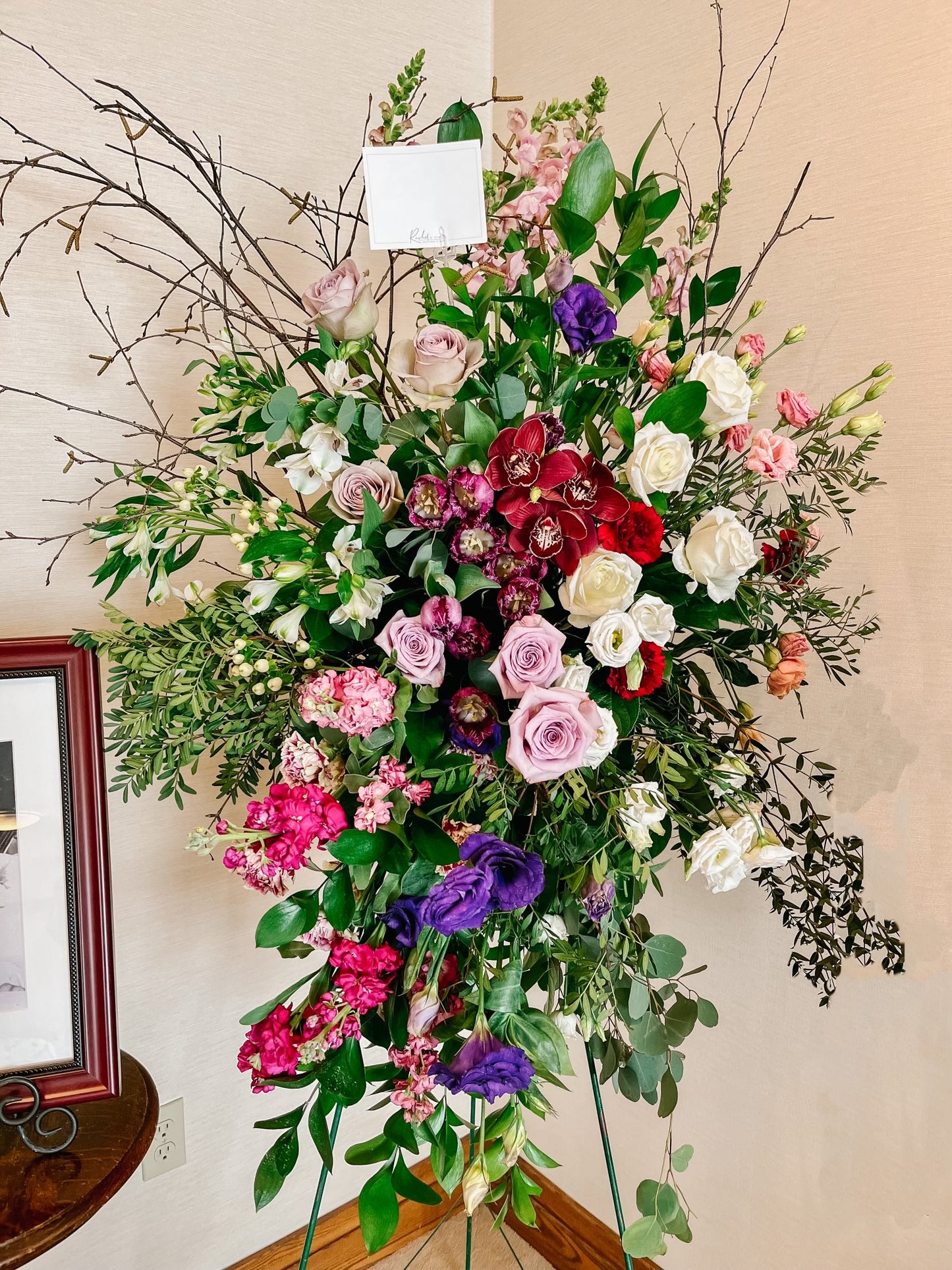 a standing sympathy spray with a varitey of florals such as roses, cimbidium orchids, lisianthus, and grenery.