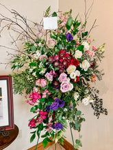 Load image into Gallery viewer, a standing sympathy spray with a varitey of florals such as roses, cimbidium orchids, lisianthus, and grenery.
